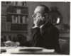 Am Schreibtisch in Pacific Palisades (740 Amalfi Drive) Beschreibung: Thomas Mann, Brustbild, Profil nach links, Zigarre in der rechten Hand, Kopf auf die linke Hand gestützt, von der Arbeit aufblickend.